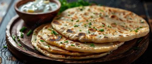 two pita breads on a wooden plate with dip at Signature Hotel in Ajmer