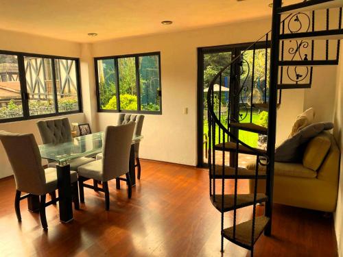 a dining room with a glass table and chairs at Alojamiento tipo Cabaña, rodeado de Bosque in Mexico City