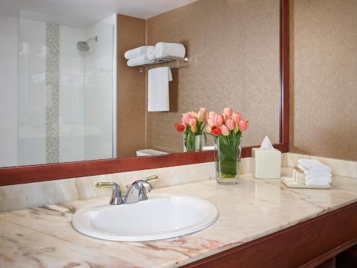 a bathroom with a sink and a vase of pink flowers at Varscona Hotel on Whyte in Edmonton