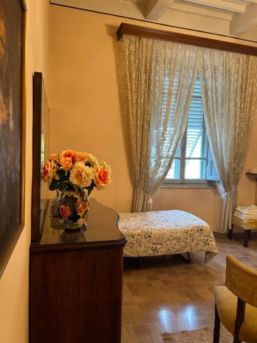 a bedroom with a window and a vase of flowers on a table at Villa Ada in Monsummano