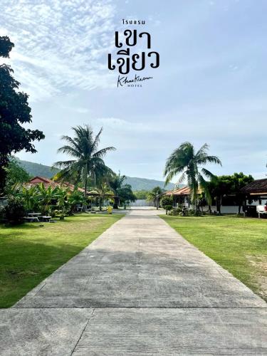a walkway with palm trees in the distance at KHAO KIEOW Hotel โรงแรมเขาเขียว in Ban Mai