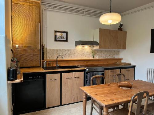 - une cuisine avec une table en bois et un lave-vaisselle noir dans l'établissement Coin champêtre cœur de bastide, à Sainte-Foy-la-Grande