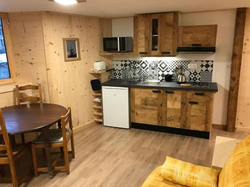 une cuisine et une salle à manger avec une table et une cuisine, ainsi qu'une table et des chaises dans l'établissement FLUMET , Appartement Espace Diamant, à Flumet