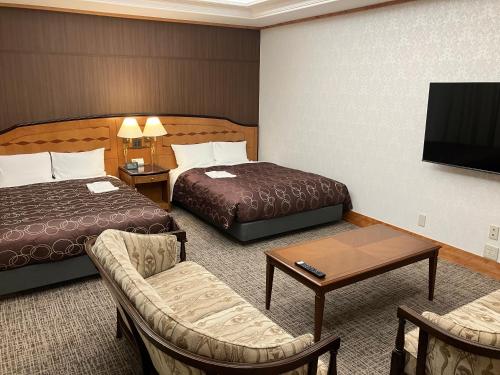 a hotel room with two beds and a tv at Racine Shinmaebashi in Maebashi