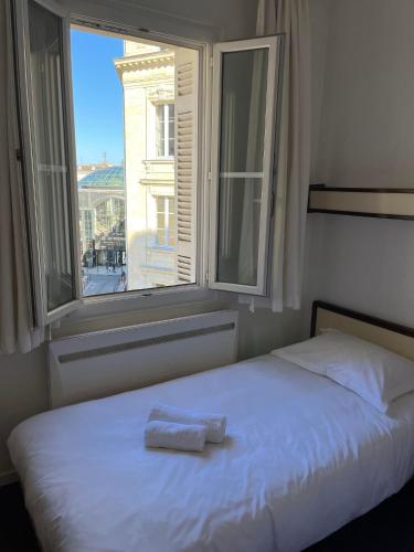 a bed with a towel on it in front of a window at Hotel Des Grands Hommes - Bordeaux Centre in Bordeaux
