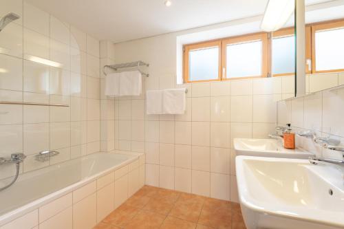 a white bathroom with a tub and a sink at Haus Emilia am Faschinajoch in Fontanella
