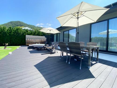 a wooden deck with tables and chairs and umbrellas at Seaside Garden Nishiizu 2 in Nishiizu