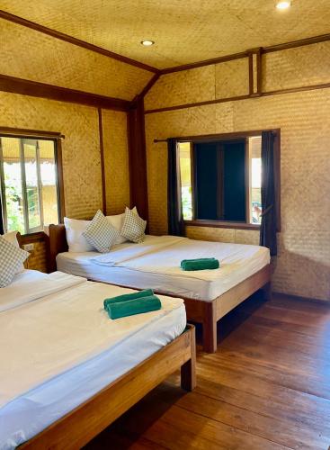 two beds in a room with two windows at Pai Homey in Pai