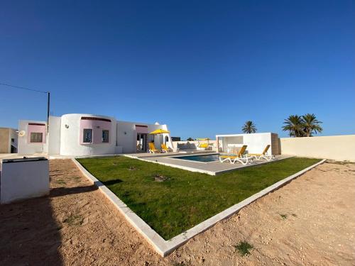 a house in the desert with a grass yard at Villa raif in Djerba