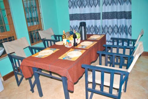 a dining room table with chairs and a table with wine bottles at Ngorongoro Villa and Restaurant in Karatu