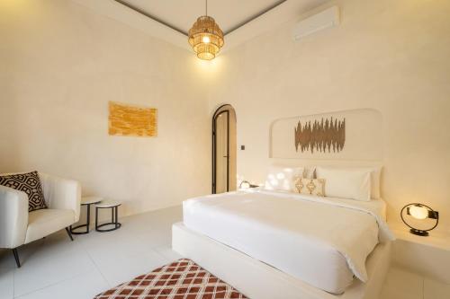 ein weißes Schlafzimmer mit einem Bett und einem Stuhl in der Unterkunft Villa Affinity Canggu by OriVista Great Location in Canggu