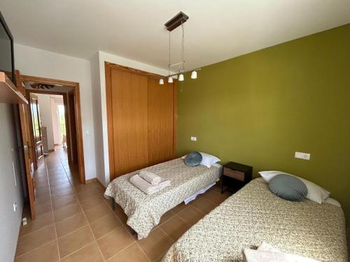 Dos camas en una habitación con paredes verdes. en Apartamento con piscinas y wifi en playas Costa Norte, en Vinarós
