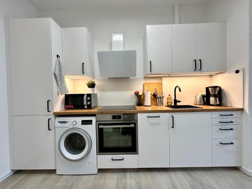 a kitchen with white cabinets and a washing machine at TOP 2 Zimmer Altbauwohnung in Kiel Mitte 24-7 Check In in Kiel