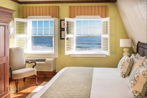 ein Schlafzimmer mit zwei Fenstern und einem Bett und einem Stuhl in der Unterkunft Elizabeth Pointe Lodge in Fernandina Beach
