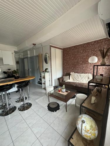un salon avec un canapé et un mur de briques dans l'établissement Duplex moderne centre du Boulou, au Boulou