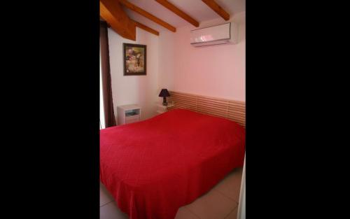 ein Schlafzimmer mit einem roten Bett mit einer roten Decke in der Unterkunft Le mazet in Saint-Mandrier-sur-Mer