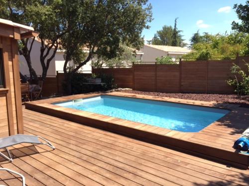 a swimming pool on a wooden deck next to a backyard at Gîte location de vacances : G2735 in Saint-Maximin-la-Sainte-Baume