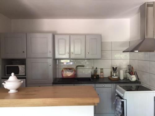 a kitchen with white cabinets and a wooden counter top at Gîte location de vacances : G2735 in Saint-Maximin-la-Sainte-Baume