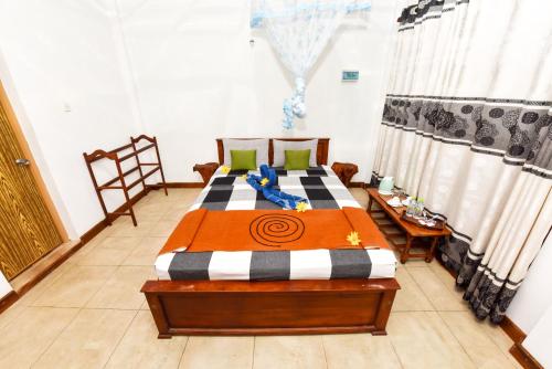 a bedroom with a bed with an orange and black blanket at Elephant Trio Sigiriya in Sigiriya