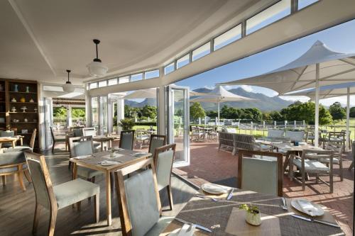 a restaurant with tables and chairs with mountains in the background at Fancourt Hotel in George