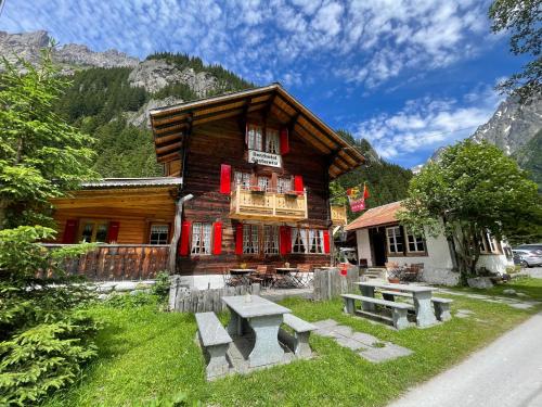 a log cabin with benches in front of it at Berghotel Gasterntal in Kandersteg
