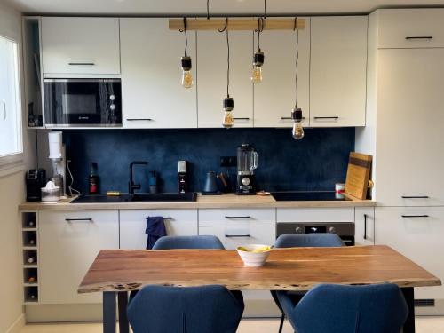une cuisine avec une table en bois et des chaises bleues dans l'établissement Familial et Confortable, à Toulouse