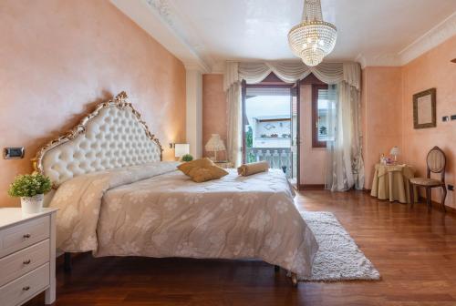 una grande camera da letto con un grande letto e un lampadario a braccio di La Casa di Tonina a Quartu SantʼElena