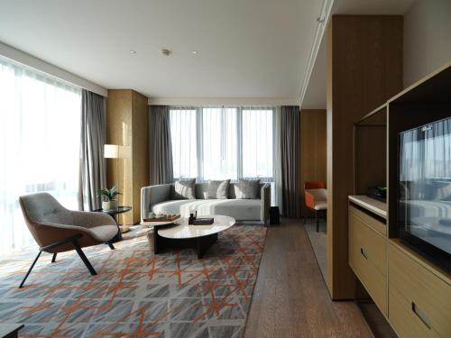 a living room with a couch and a tv at The Qube Hotel Anqing in Anqing