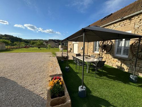 a table with an umbrella in front of a house at L’ÉCURIE in Gigny