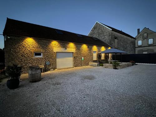 a brick building with a garage with a driveway at L’ÉCURIE in Gigny