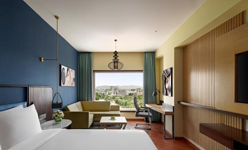 a hotel room with a bed and a couch at Ramada Encore by Wyndham Udaipur Roopnagar in Udaipur