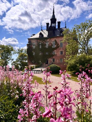 an old castle with pink flowers in front of it at Wiks Slott in Vik