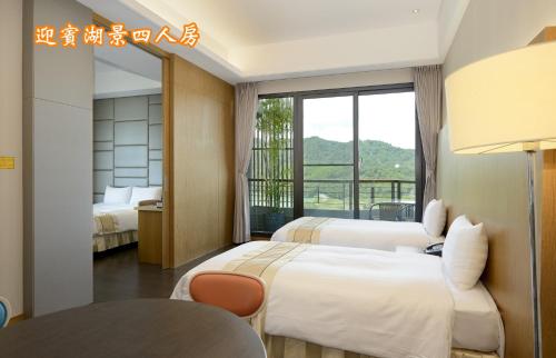 a hotel room with two beds and a window at Sun Moon Lake Teachers' Hostel in Yuchi