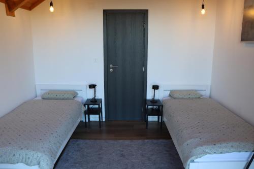 two beds in a room with a door and two chairs at Copanjek Country House in Plešivica