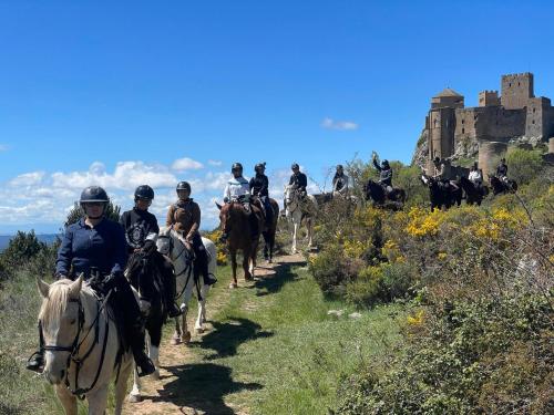 a group of people riding horses on a hill with a castle at Solano de Moran in Murillo de Gállego