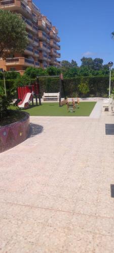 a park with a playground with benches and a building at Cala Blanca on the beach in El Borseral