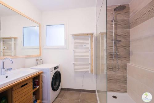 La salle de bains est pourvue d'un lave-linge et d'une douche en verre. dans l'établissement Appartement Biscarrosse joli T3 avec terrasse et jardin privatif classé 1 étoile, à Biscarrosse