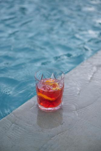 a glass filled with fruit next to a swimming pool at Matala Bay Hotel in Matala