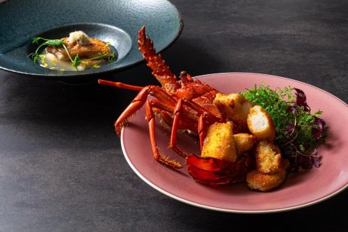 a pink plate with a lobster and a dish of food at Kyoto Brighton Hotel in Kyoto