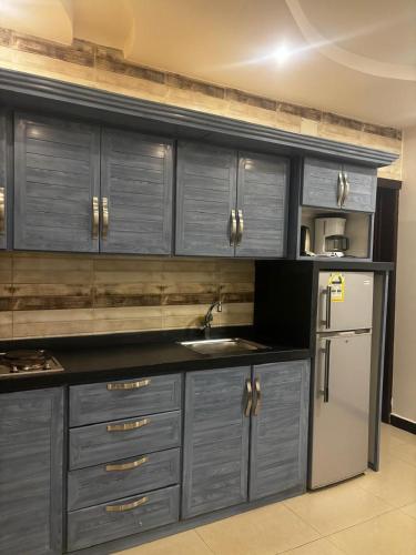 a kitchen with gray cabinets and a stainless steel refrigerator at Ramis Furnished Units in Buraydah