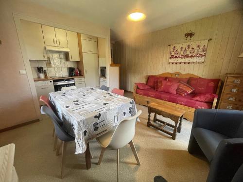 un salon avec une table et un canapé rouge dans l'établissement Gemeaux B, appartement proche pistes de ski et village, à La Clusaz
