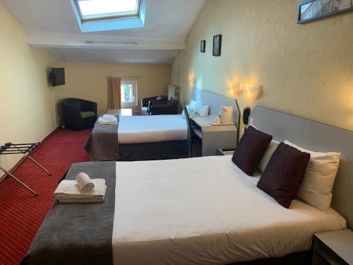 a hotel room with two beds and a desk at Brit Hotel Bleu Nuit in Saintes