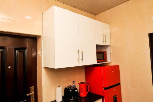 a kitchen with a red refrigerator and white cabinets at Haven Heights Apartments in Lagos