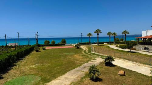 un parco con palme e l'oceano sullo sfondo di Anemos Deluxe Poseidi Apartments a Possidi