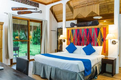 a bedroom with a large bed and a large window at Daluyon Beach and Mountain Resort in Sabang