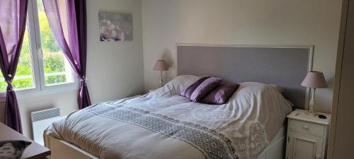 - une chambre avec un lit doté d'oreillers violets et d'une fenêtre dans l'établissement Le mas de malatra cavalaire, à Cavalaire-sur-Mer