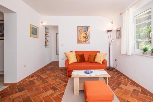 a living room with an orange couch and a table at Belina apartment for two in Punat