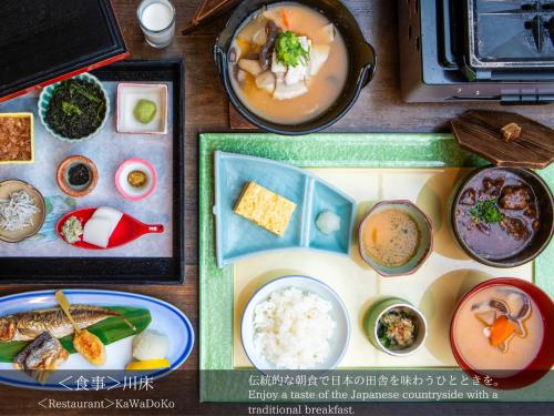 a table topped with different types of food on plates at Tatsuta Ryokan in Izu