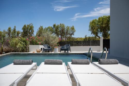 ein Swimmingpool mit weißen Tischen und Stühlen daneben in der Unterkunft Mons Villa in Kalathas