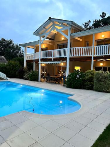 une maison avec une piscine devant une maison dans l'établissement Splendide villa au cœur du Golf Lacanau Océan, à Lacanau-Océan